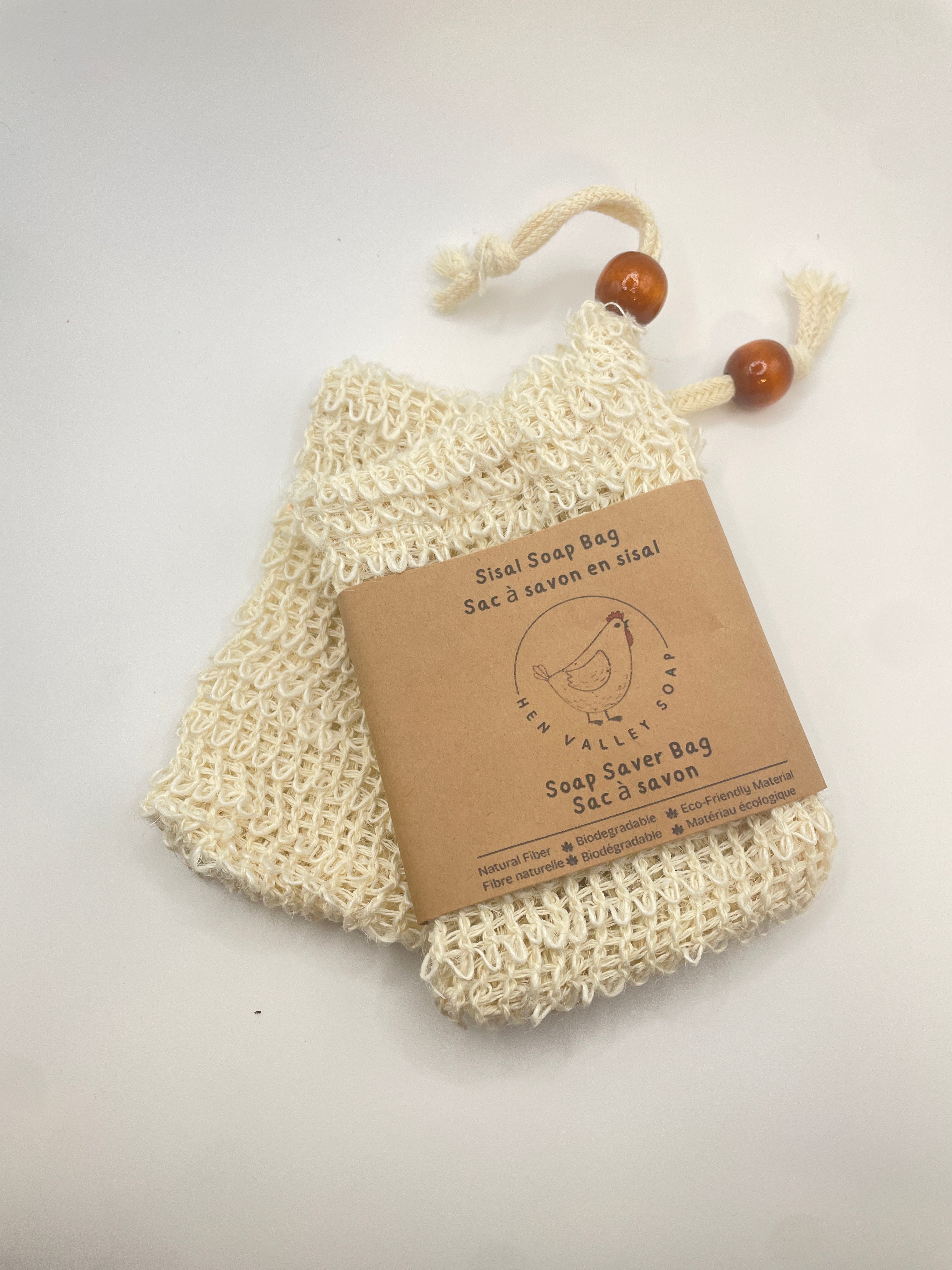 Bar of soap in a natural fiber bag with a wooden handle on a white background